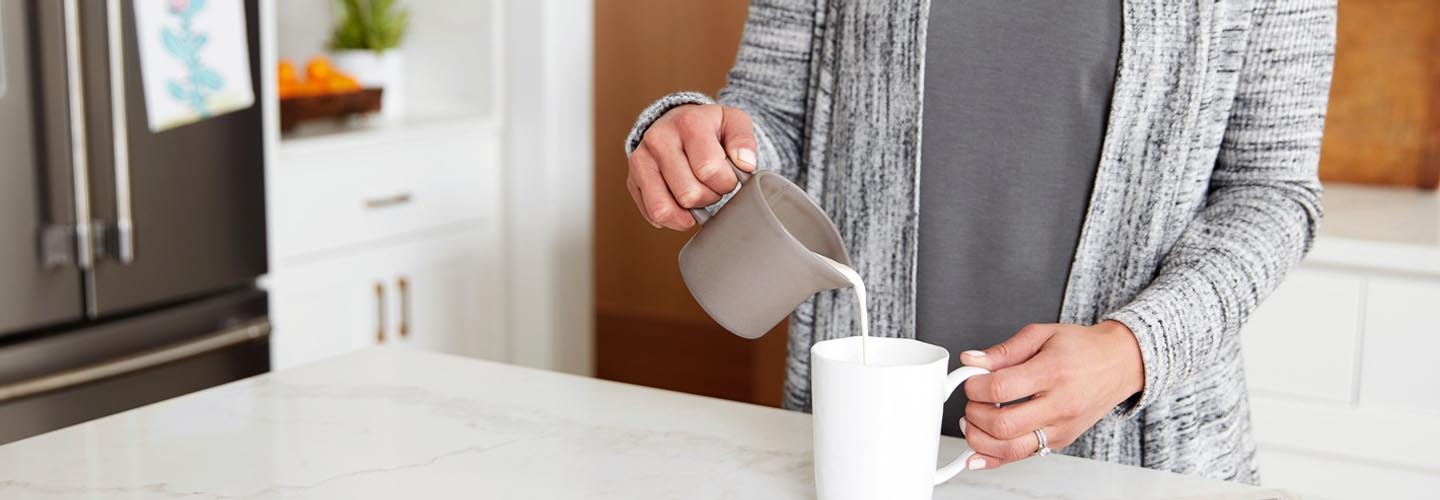 Woman pouring milk into coffee mug