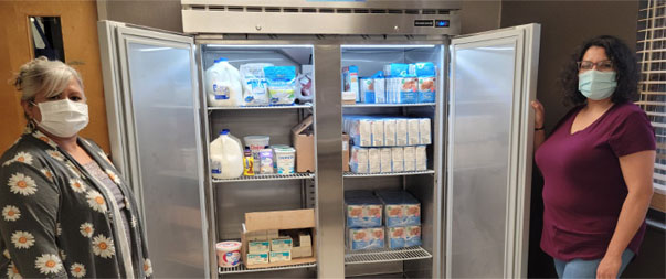 Women displaying their dairy refrigerator