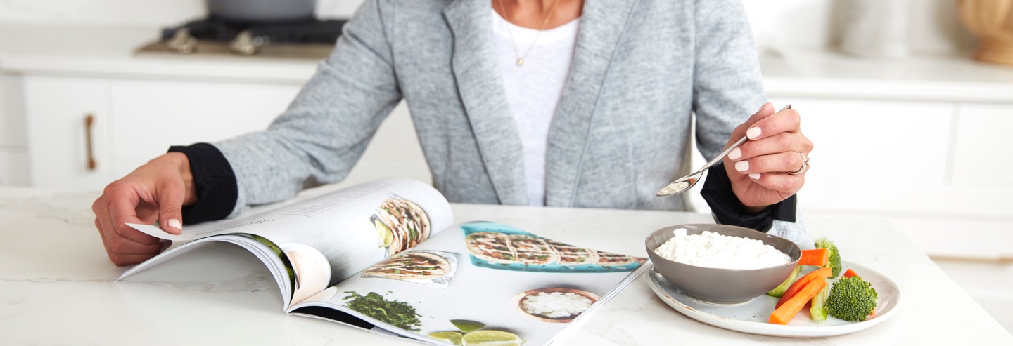 Woman eating cottage cheese looking at a magazine