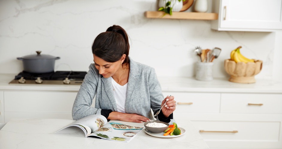 Woman eating cottage cheese looking at a magazine