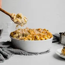 Spinach-Art-Mac-5-copy.webp A spoon dipping into a creamy dish of macaroni and cheese.